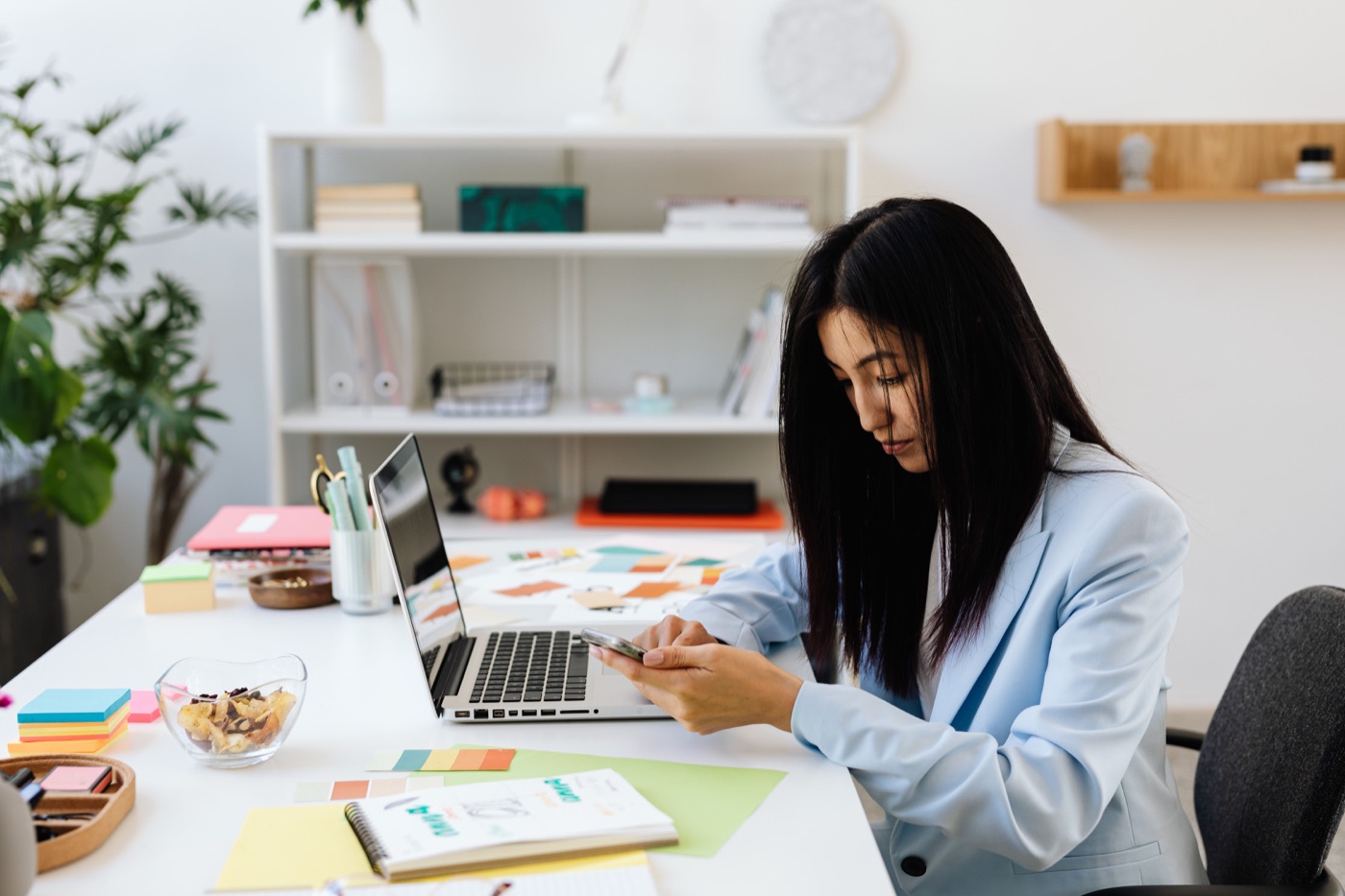 A professional reviewing her smartphone at a desk with creative planning materials